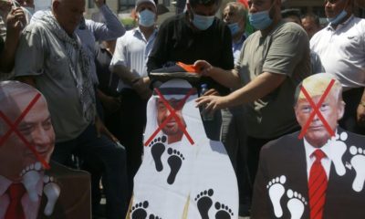 Palestinians place shoes on pictures of American Israeli and Emirati leaders during a protest against the UAEs deal with Israel in Nablus West Bank Aug 14 2020