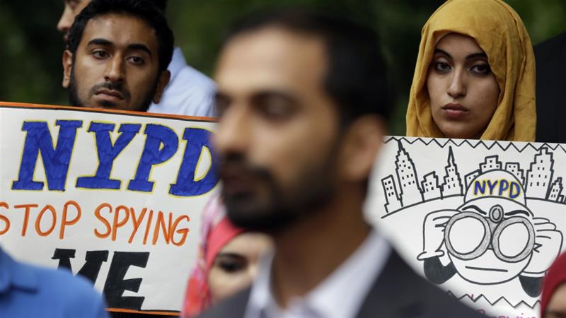 People hold signs while attending a rally to protest the New York Police Departments surveillance tactics near its headquarters in New York on August 28 2013