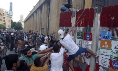 Protesters try to remove a concrete barrier to open a road leading to the parliament building during an anti government protest in Beirut Lebanon on August 10 2020