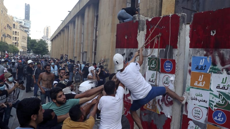 Protesters try to remove a concrete barrier to open a road leading to the parliament building during an anti government protest in Beirut Lebanon on August 10 2020