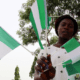 A Nigerian holding multiple Nigerian flags