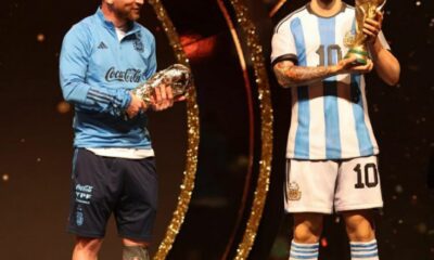 Lionel Messi with a statue of himself holding the World Cup