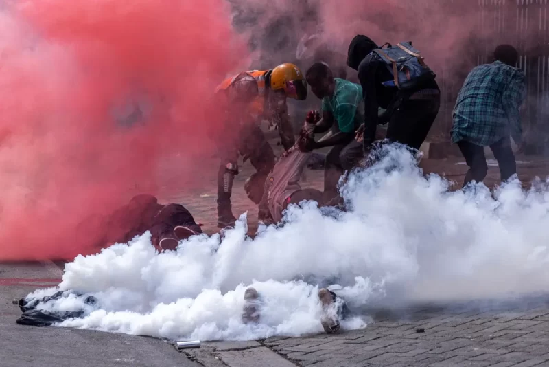 Protesters try to help injured people outside the Kenya Parliament during a nationwide strike to protest against tax hikes and the Finance Bill 2024 in downtown Nairobi, on June 25, 2024. – Kenyan police shot dead one protester near the country’s parliament Tuesday, a rights watchdog said as demonstrators angry over proposed tax hikes breached barricades and entered the government complex, where a fire erupted. The mainly Gen-Z-led rallies, which began last week, have taken President William Ruto’s government by surprise, with the Kenyan leader saying over the weekend that he was ready to speak to the protesters. (Photo by LUIS TATO / AFP)