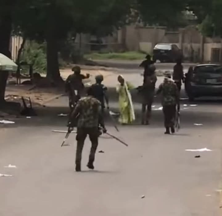 A photo shows Nigerian Army Guards Brigade officers arresting and beating a teenage girl during the protest.